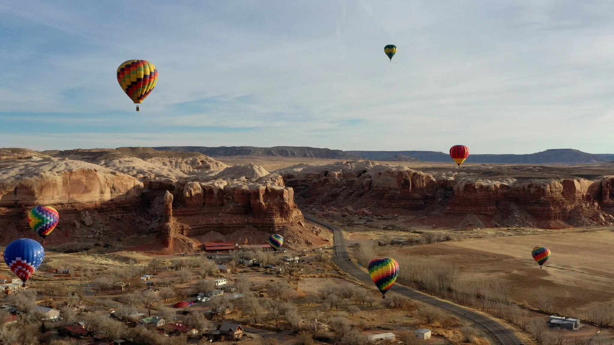Balloons floating above the pale sandstone folds of Bluff.