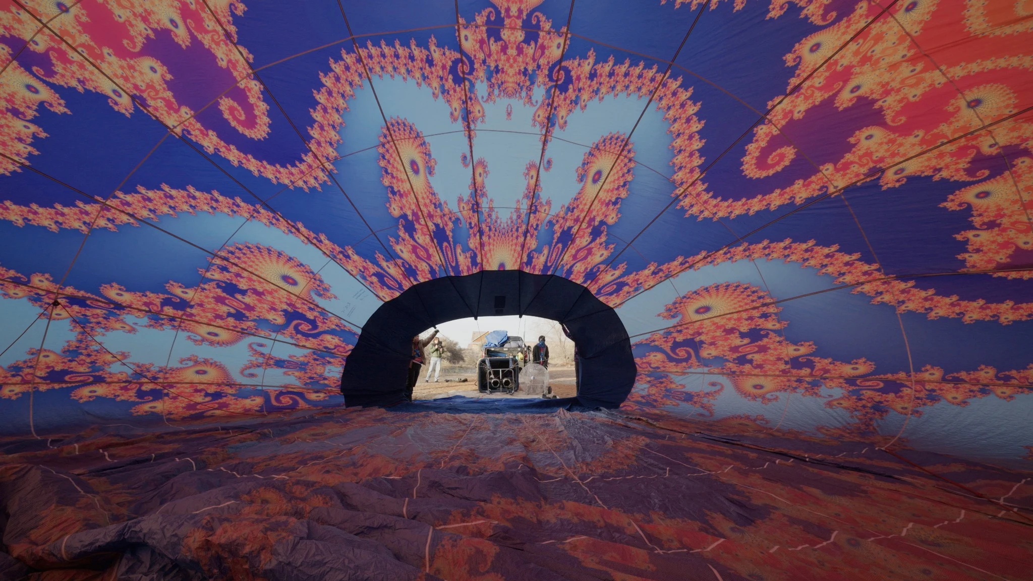 The patterned interior of a balloon envelope, with people framed in its opening.