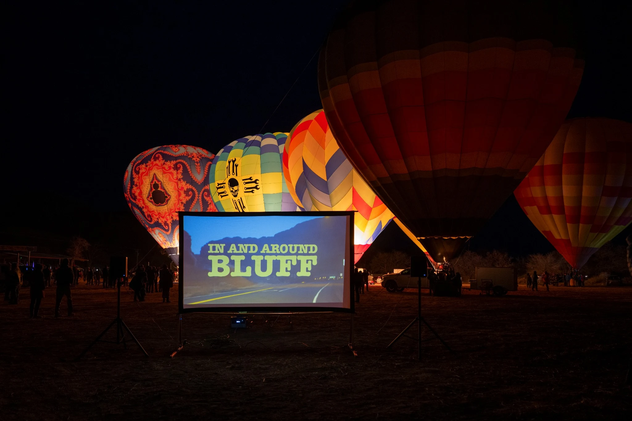 In and Around Bluff projected outdoors in front of glowing balloons at night.