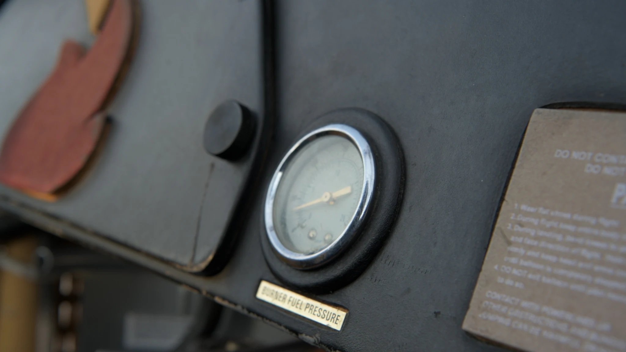 A close view of the burner fuel-pressure gauge and worn flight equipment.