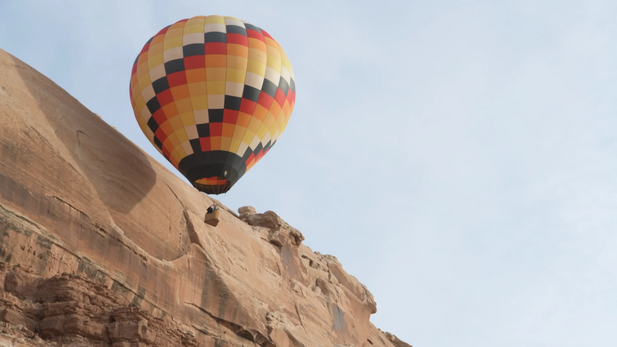 A checkered balloon skimming the sandstone cliffs above Bluff.