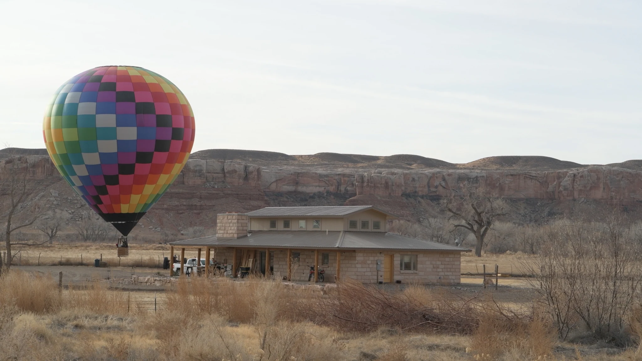 A rainbow-colored balloon floating beside a house beneath the bluffs.