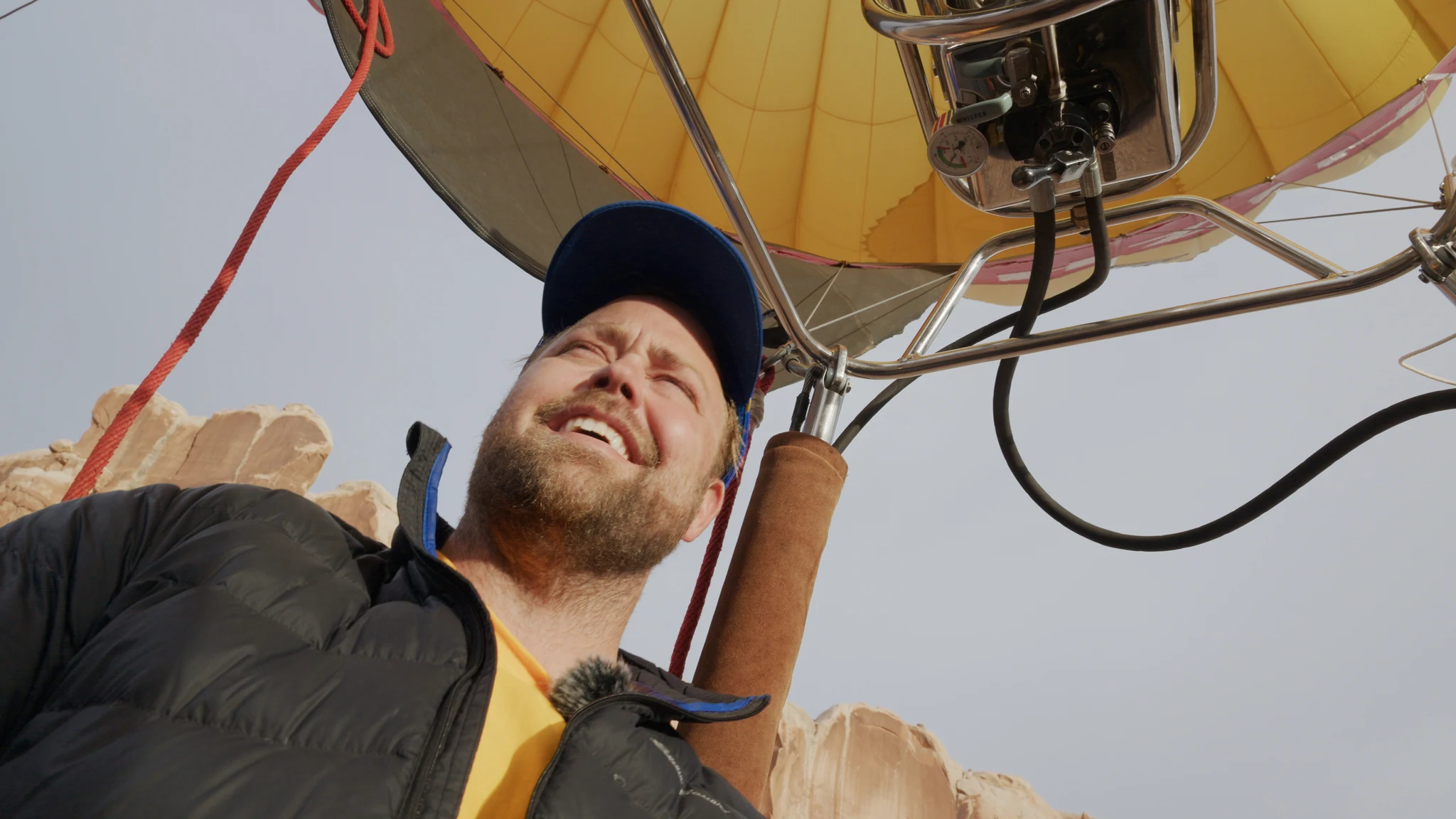 A smiling passenger beneath a balloon burner and yellow envelope.