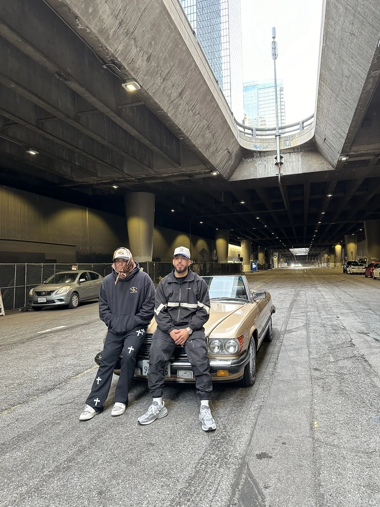 Pirate Worldwide beside a convertible beneath a Los Angeles overpass