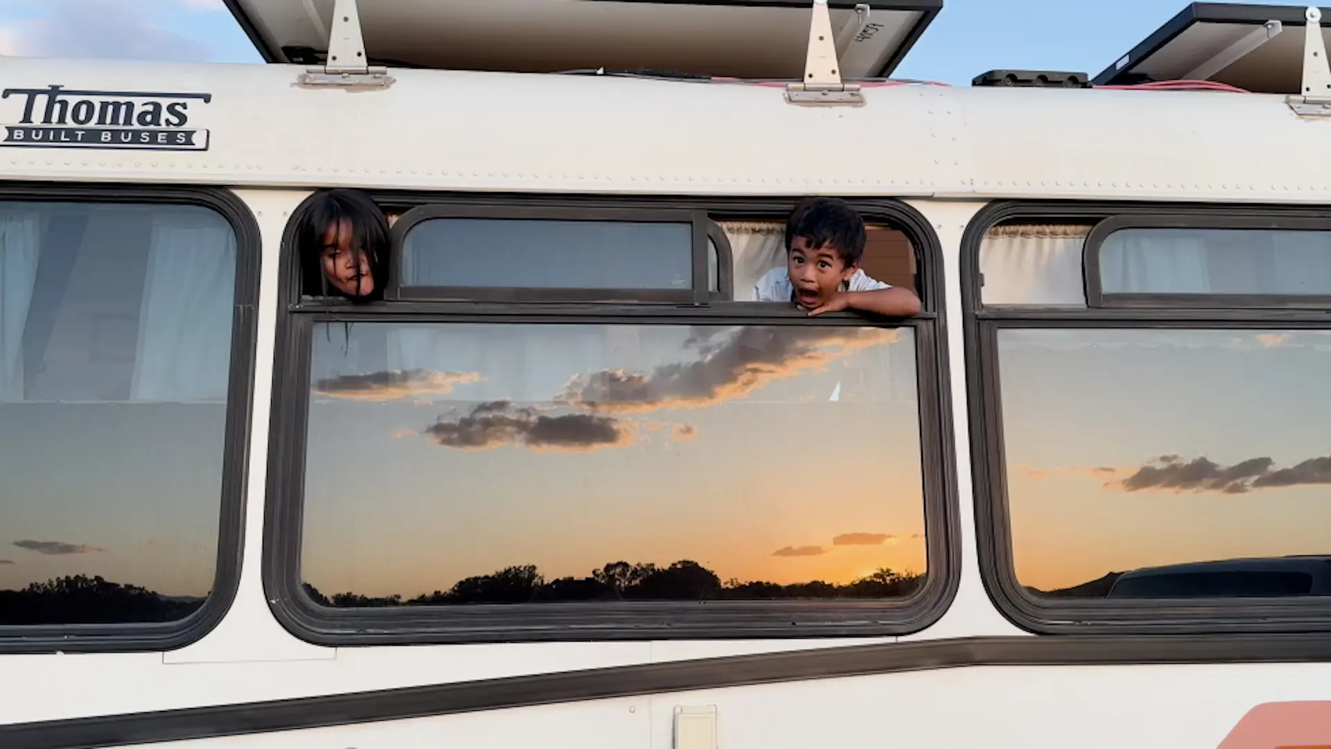 Two children looking through Sunny’s windows at sunset